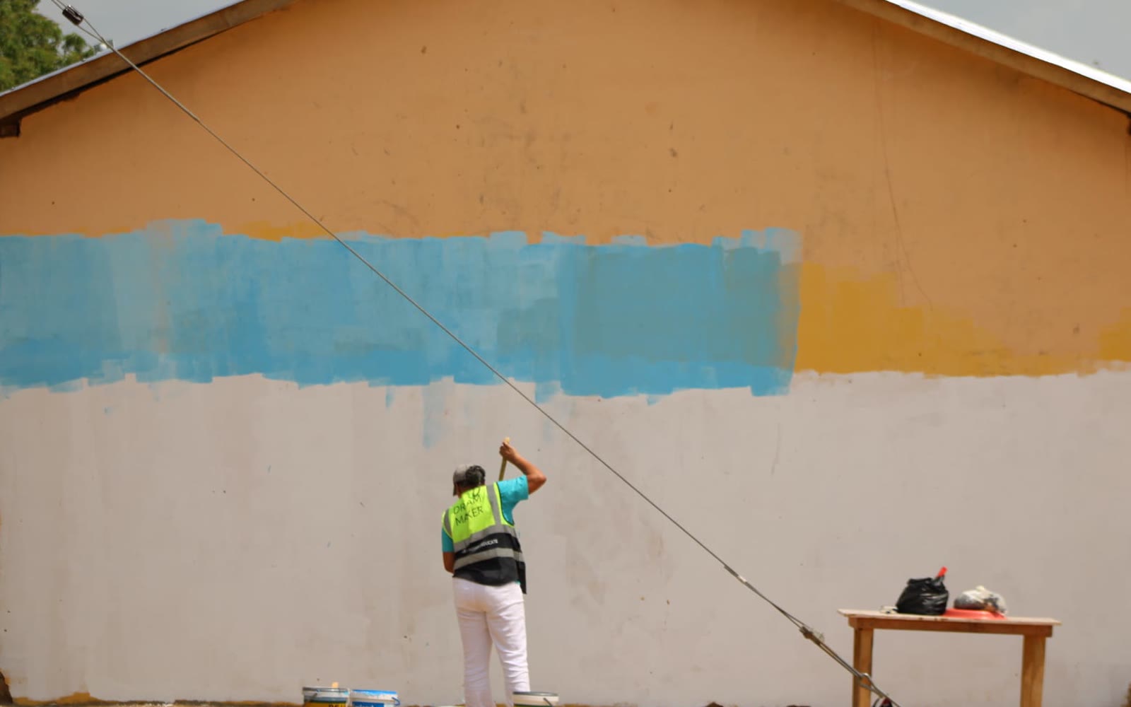 Before: volunteers priming a plain classroom wall
