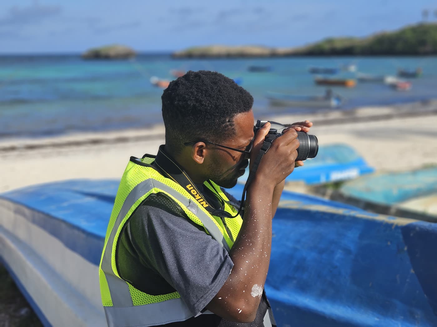 A volunteer photographing fishing boats on a turquoise shore