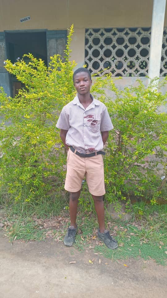 Bismark, a Dadome DA Basic School student, standing outside his classroom