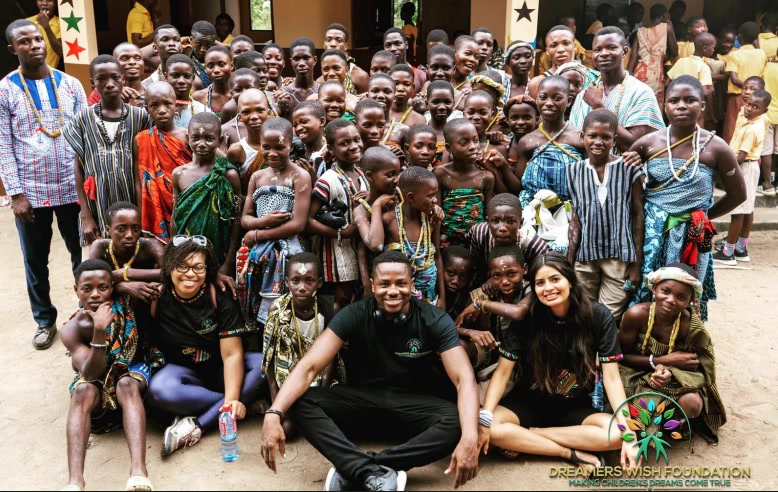 Godwill sitting on the ground with students and founding volunteers at our first partner school in Ghana