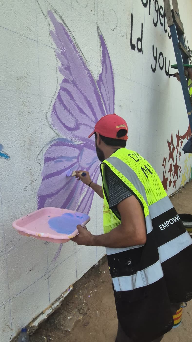 A volunteer painting a purple butterfly