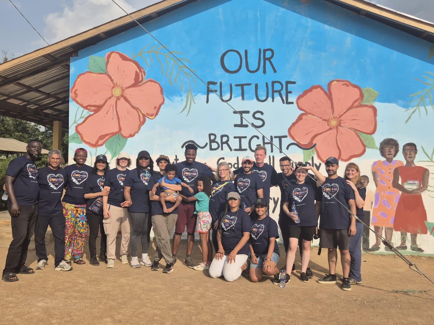 Volunteers and students in front of the Our Future Is Bright mural