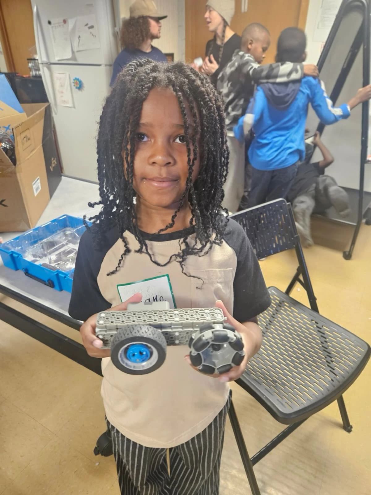 A girl in our Utah robotics class proudly holds the VEX robot she built